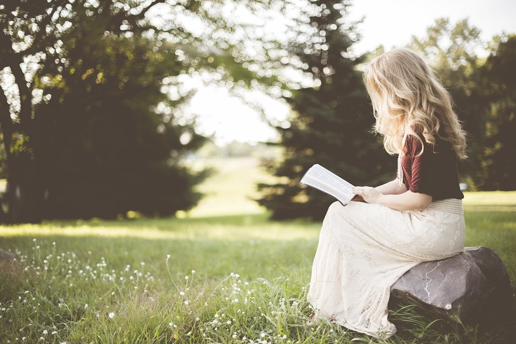 Jeune fille qui lit un livre dans un parc