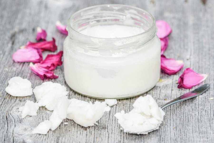 Un pot d'huile de coco avec une cuillère et des fleurs