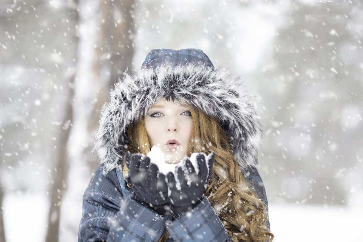 Femme qui souffle dans la neige en hiver