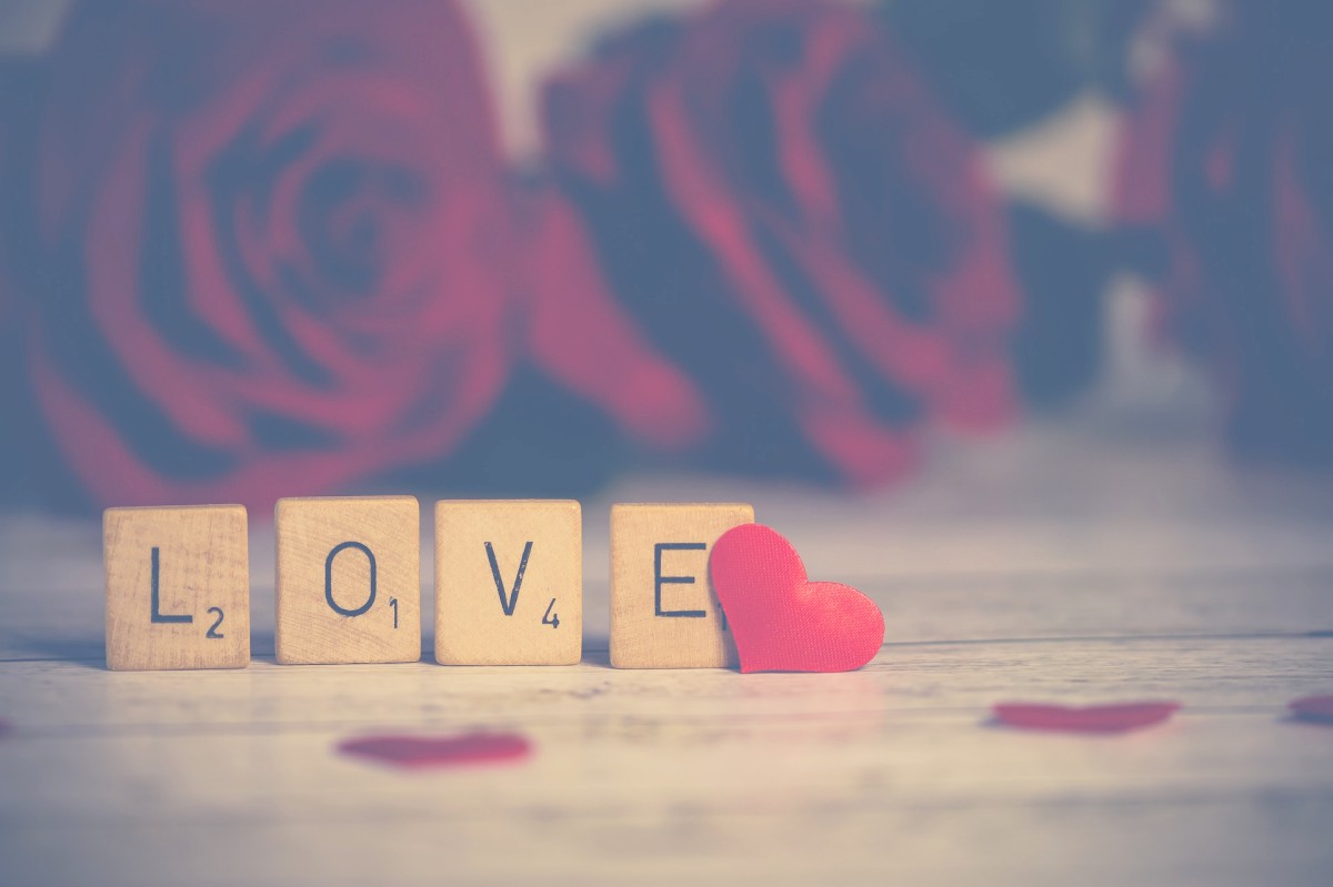 Love écrit en lettres de Scrabble avec des coeurs et des fleurs