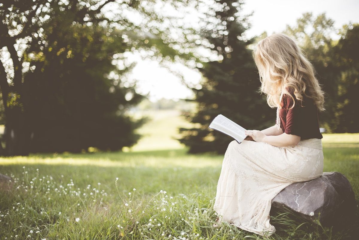 Fille qui lit un livre dans un parc. H et la plume de l'espoir