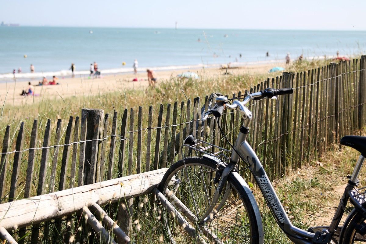 Photo d'un vélo contre les barrières donnant accès à une plage de Charente Maritime