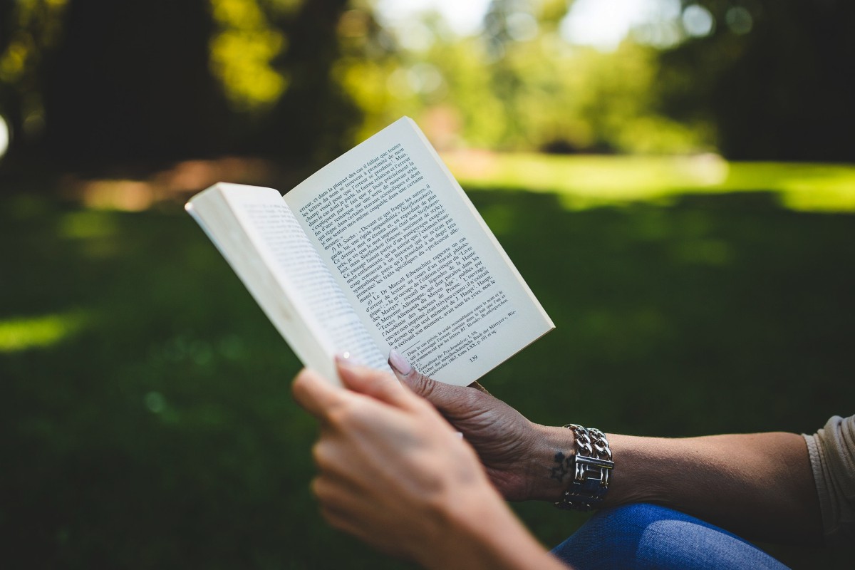 Femme qui lit un livre dans un parc