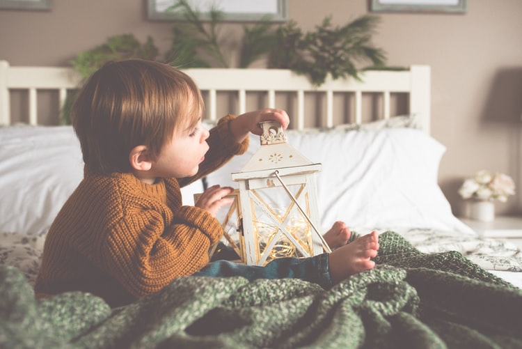 Petit garçon de 2 ans qui joue sur un lit d'adulte