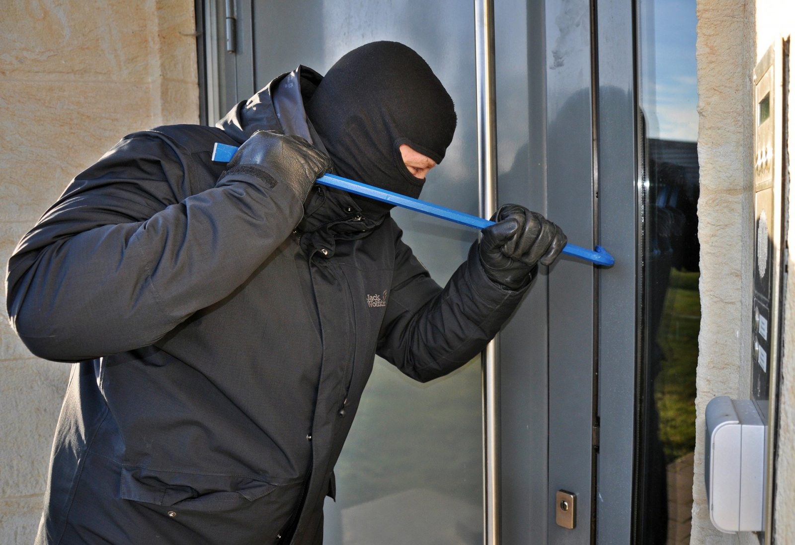 Homme masqué qui essaie d'entrer dans une maison par effraction