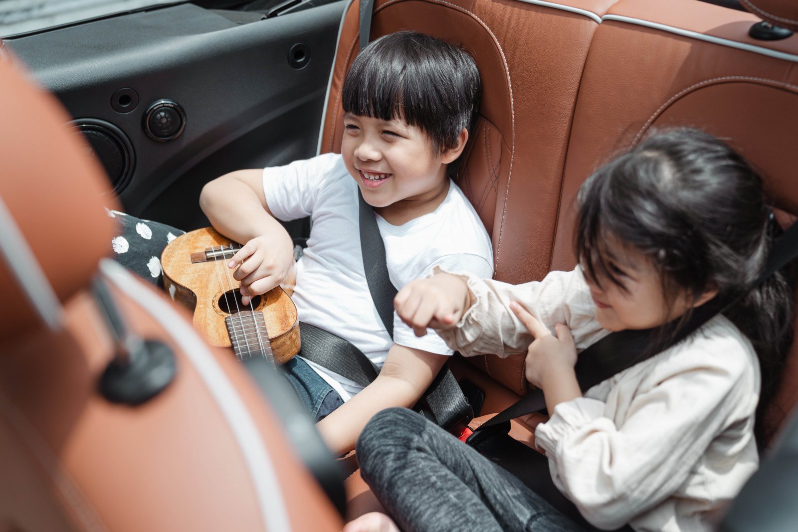 Deux enfants en train de jouer sur la banquette arrière d'une voiture, sur la route des vacances