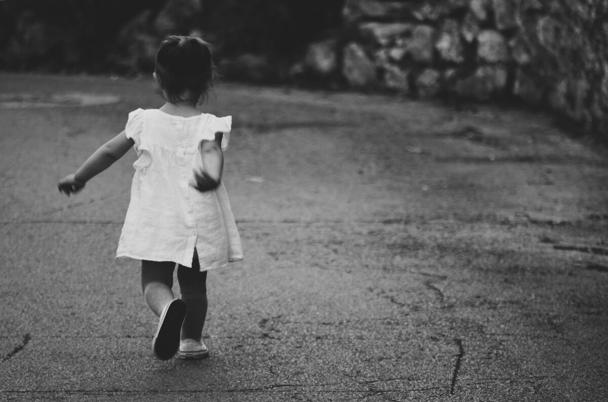 Petite fille en robe qui court dans un chemin de campagne