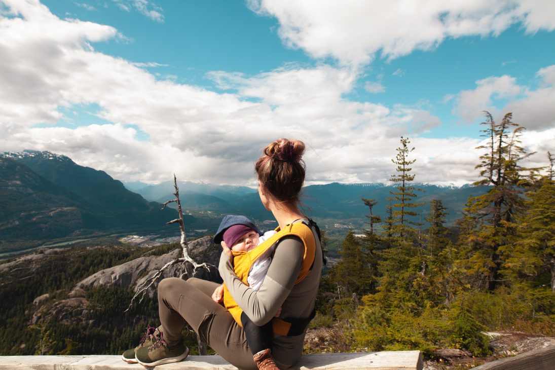 Femme et son bébé en porte bébé à la montagne