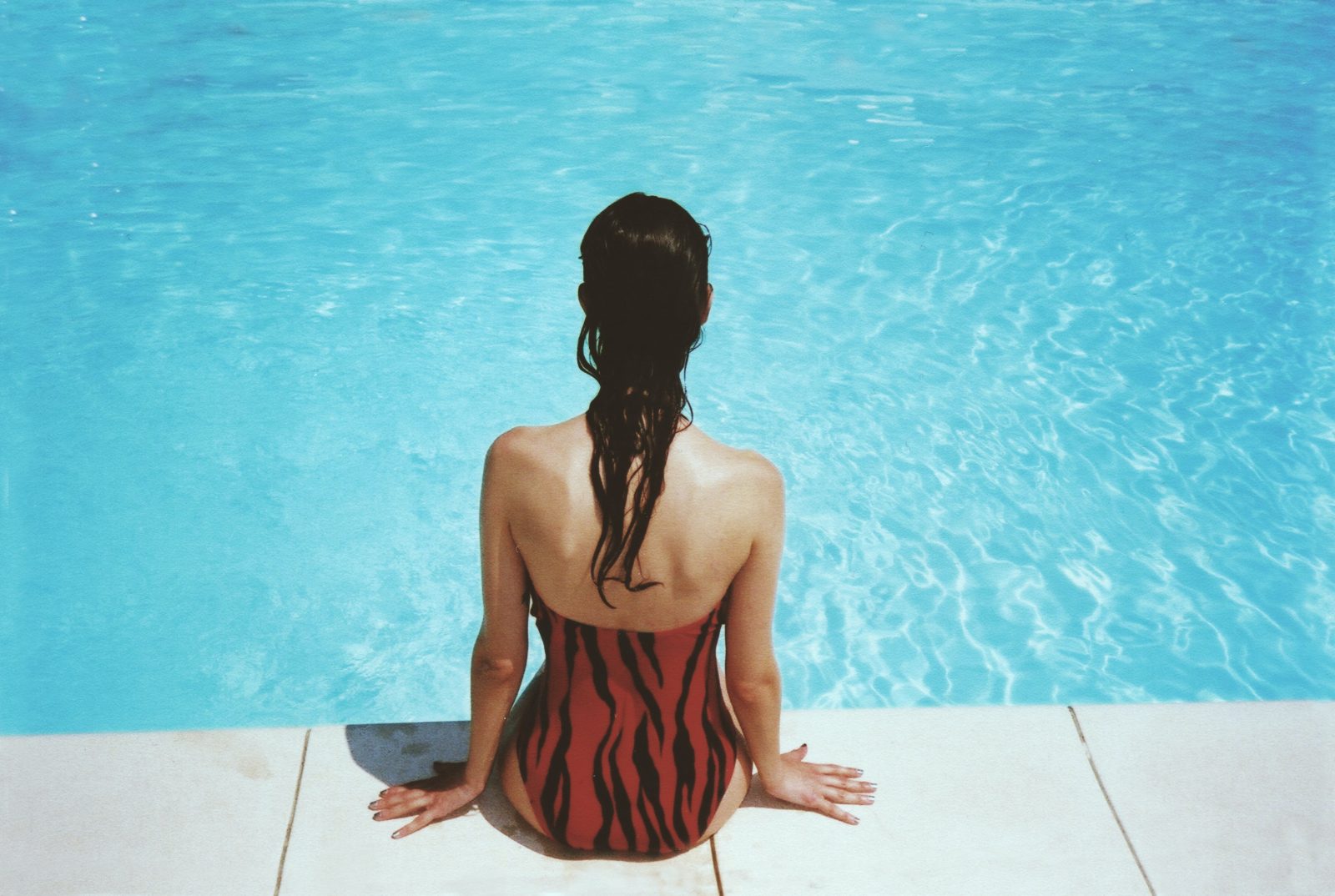 Femme au bord de la piscine au soleil en été