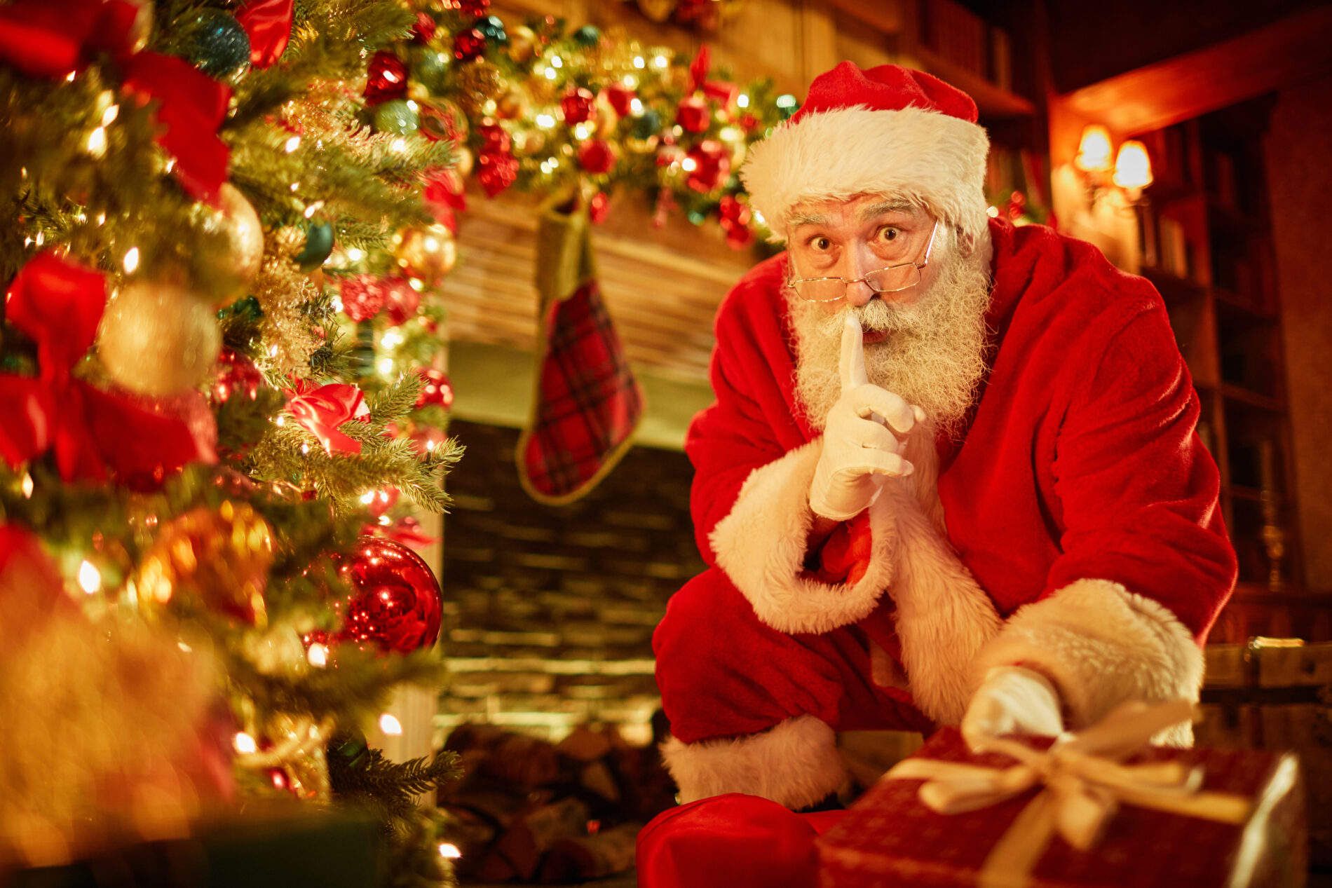 Père Noël discret au pied du sapin illuminé